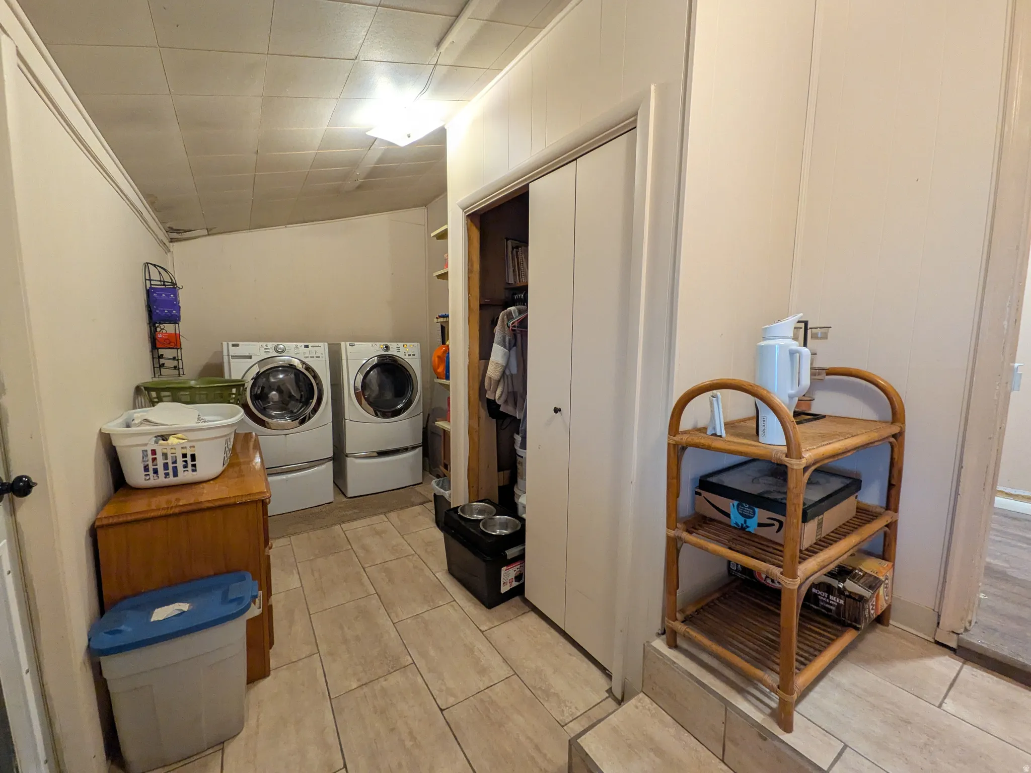 Laundry area featuring tile flooring, paneled walls, and a built-in closet with bi-fold doors