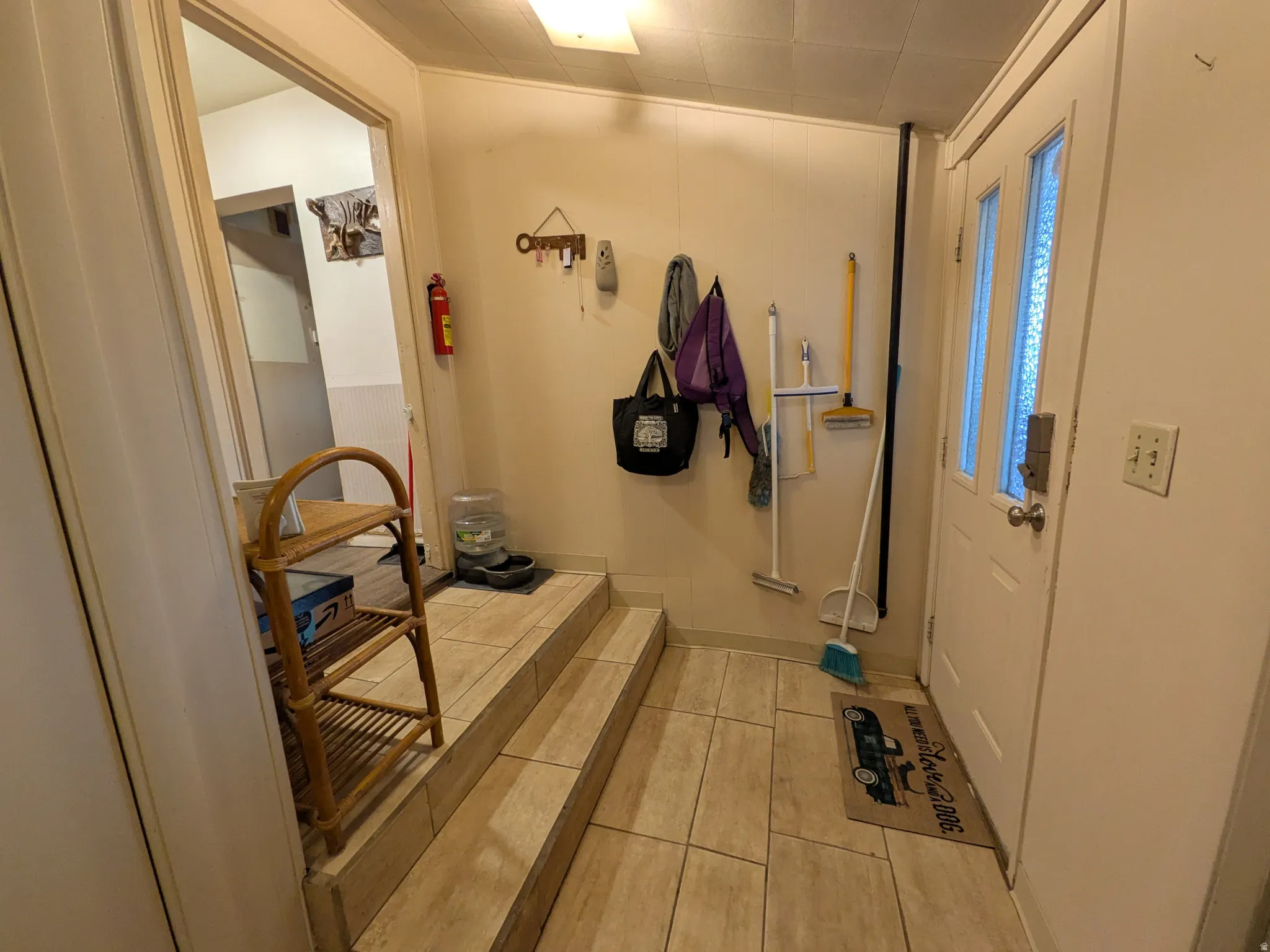 Entryway featuring a white paneled door with dual frosted glass inserts, light-toned tile flooring, and a multi-level floor plan