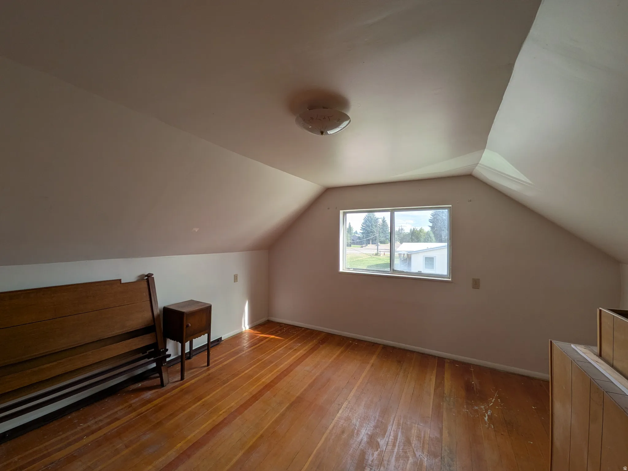 Sloped ceilings, wood-finish flooring, and a single window provide natural illumination