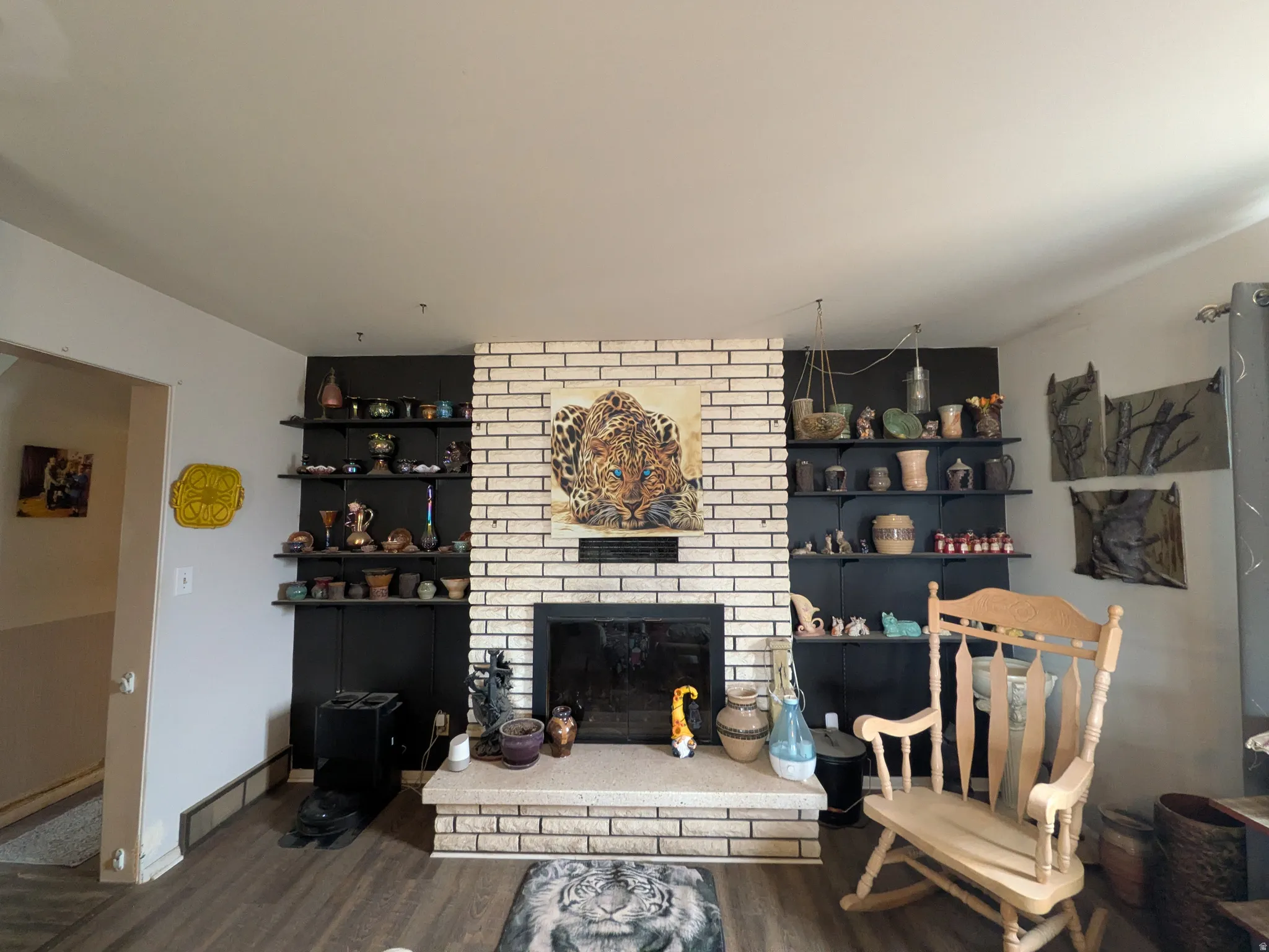 Brick fireplace with hearth, built-in shelving, wood-finish flooring, and painted walls
