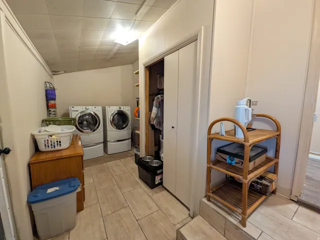 Laundry area featuring tile flooring, paneled walls, and a built-in closet with bi-fold doors
