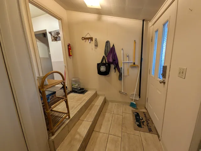 Entryway featuring a white paneled door with dual frosted glass inserts, light-toned tile flooring, and a multi-level floor plan