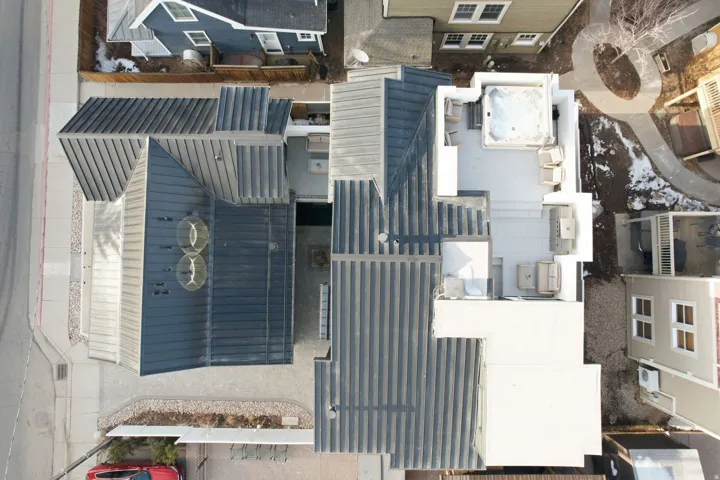Metal roofing on multiple structures, rooftop deck with integrated spa, outdoor kitchen area, and paved walkways