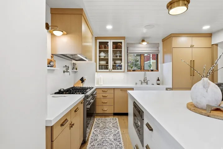 Kitchen featuring wood-finish cabinetry, white countertops, built-in stainless steel appliances, a white farmhouse sink, and a beadboard ceiling