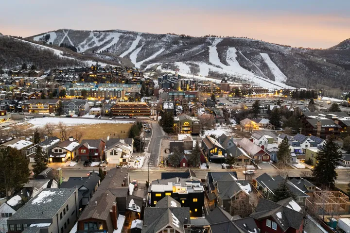 Mountain backdrop featuring snow-covered slopes, residential properties, and illuminated community buildings