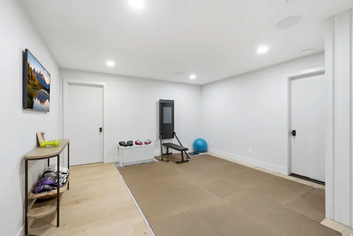Recessed lighting, wood-finish flooring, white walls, and flat panel doors with black hardware