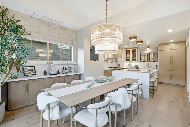Open-concept dining area with wood-finish flooring, a tiered chandelier, built-in cabinetry, and a stone accent wall