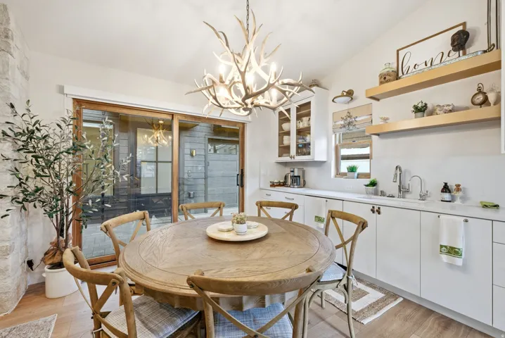Dining area featuring a decorative antler chandelier, wood-finish flooring, and a stone accent wall