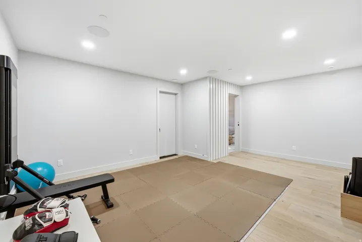 Recessed lighting with in-ceiling speakers, light wood-finish flooring, and a decorative slatted wall feature