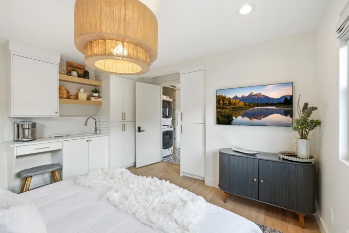 Built-in kitchenette with a stainless steel sink, white cabinetry, and open shelving