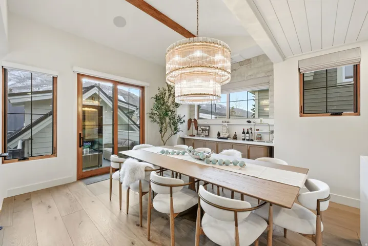 Wood-finish flooring with exposed ceiling beams and a tiered chandelier
