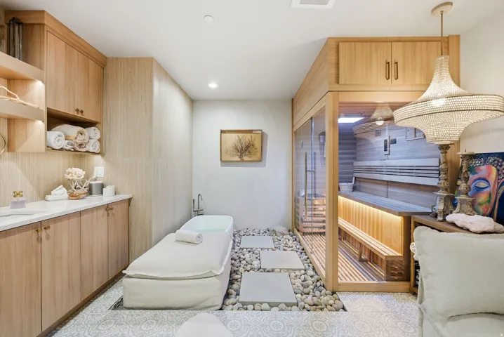 Built-in sauna with glass enclosure, soaking tub, wood-finish cabinetry, and decorative pendant lighting