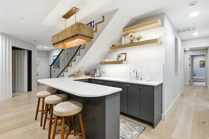 Built-in wet bar with dark cabinetry, undermount sink, and light countertops