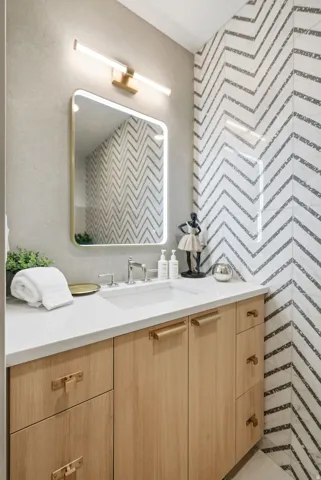 Wood-finish vanity with integrated sink, stone-finish countertop, and brass hardware