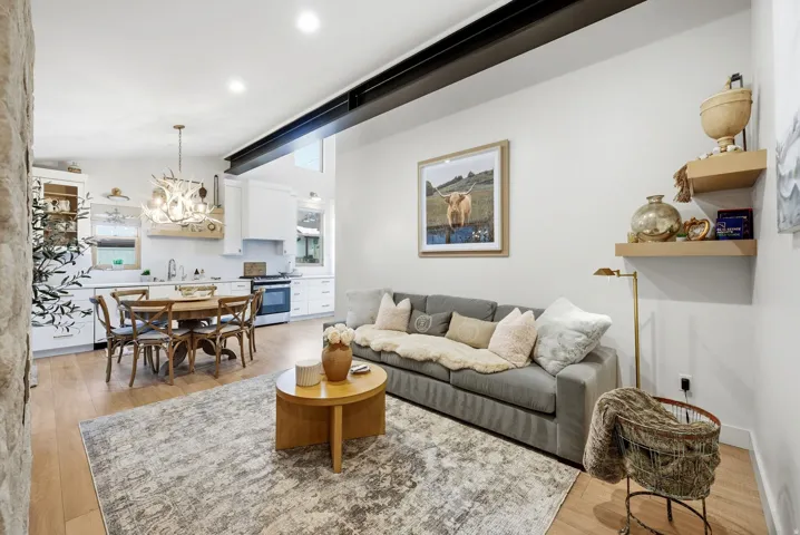 Open-concept living area with wood-finish flooring, exposed structural beam, recessed lighting, and built-in kitchen cabinetry