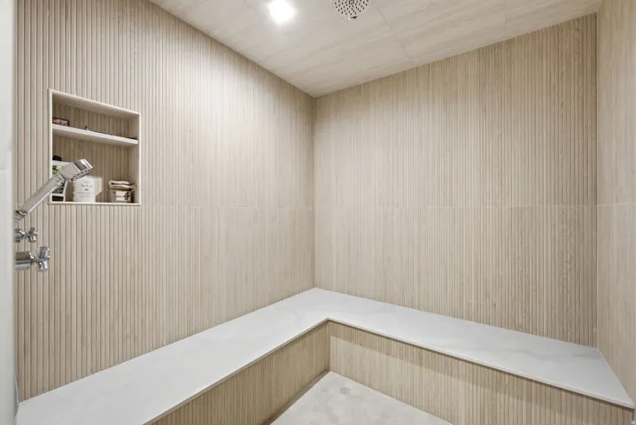 Textured wall tiling complemented by recessed shelving and a built-in bench