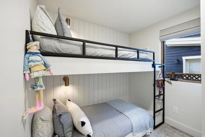 Efficient bedroom featuring built-in bunk bed with black metal framing, integrated ladder access, and under-bed storage