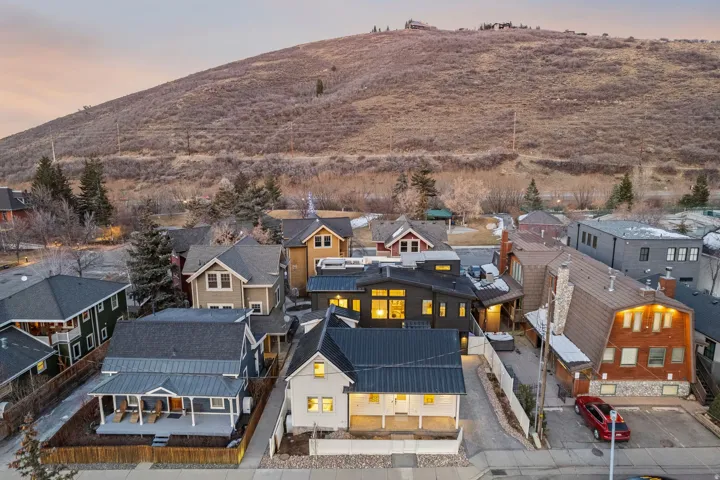 Modern exterior with a contrasting metal roof, prominent front porch, and surrounding hardscaping