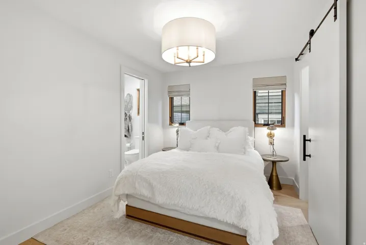White walls with wood-finish flooring, two large windows, a built-in light fixture, and a sliding barn door