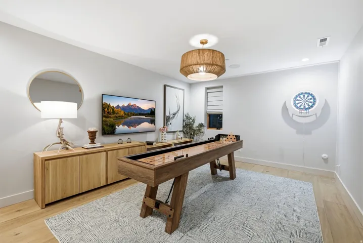 Light wood-finish flooring, recessed lighting, and a window with a Roman shade