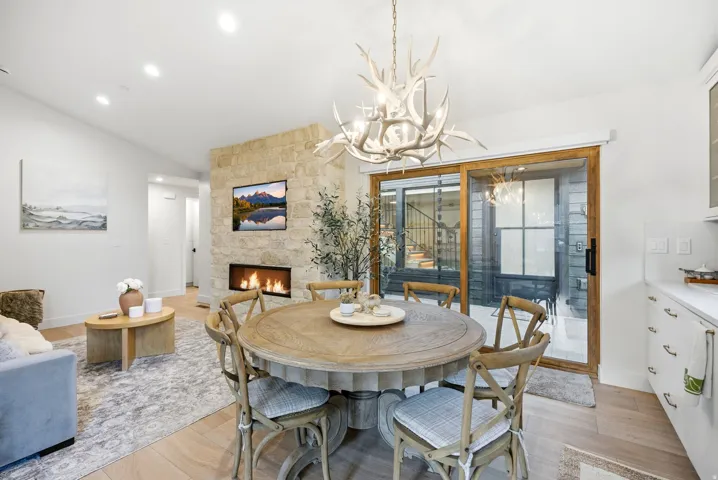 Stone-clad fireplace with a linear firebox, wood-finish flooring, recessed lighting, and a sliding glass door with wood trim
