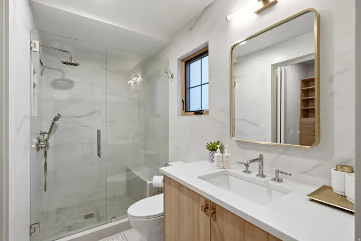 Glass-enclosed shower with a built-in bench, rainfall showerhead, and handheld sprayer