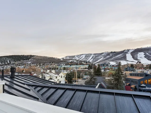 Metal roof system with a stucco and siding parapet, providing expansive mountain scenery