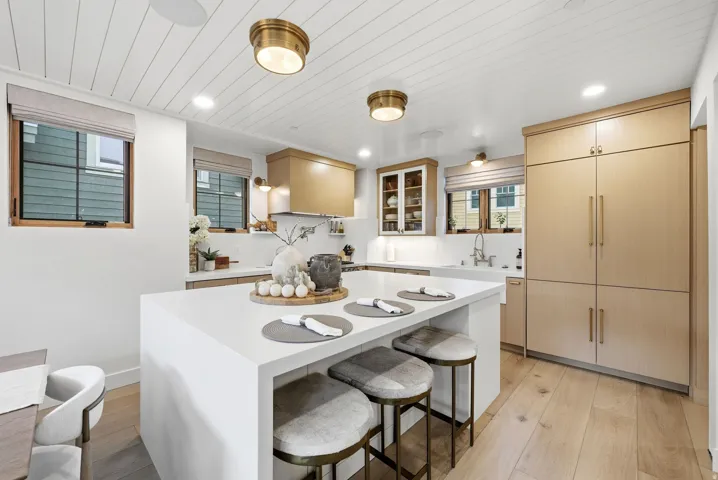 Kitchen featuring light wood-finish flooring, a waterfall island with a solid surface countertop, paneled appliances, custom cabinetry, and a shiplap ceiling with recessed and flush-mount lighting