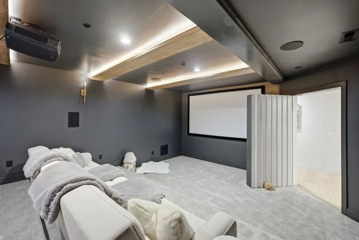 Home theater featuring a large projection screen, wall-mounted projector, recessed lighting, and integrated ceiling speakers