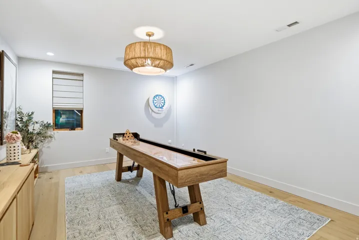 Recessed lighting, wood-finish flooring, and a window with Roman shade