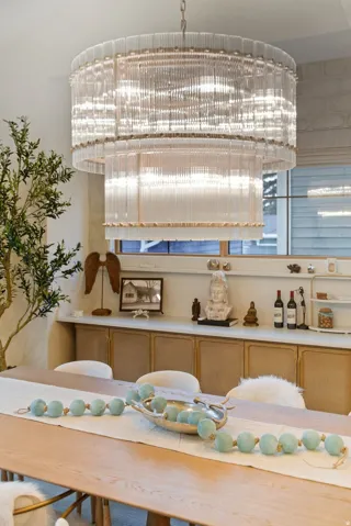 Two-tier chandelier with glass rod detailing, wood-finish dining table, and built-in cabinetry with a light-toned countertop