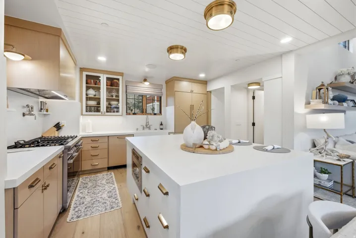 Kitchen featuring a large center island, wood-finish flooring, stainless steel range, light wood cabinetry, and recessed lighting