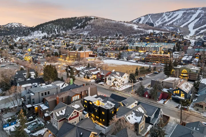 Mountainous landscape featuring a residential community with diverse architectural styles, visible streets, and a prominent ski resort in the background