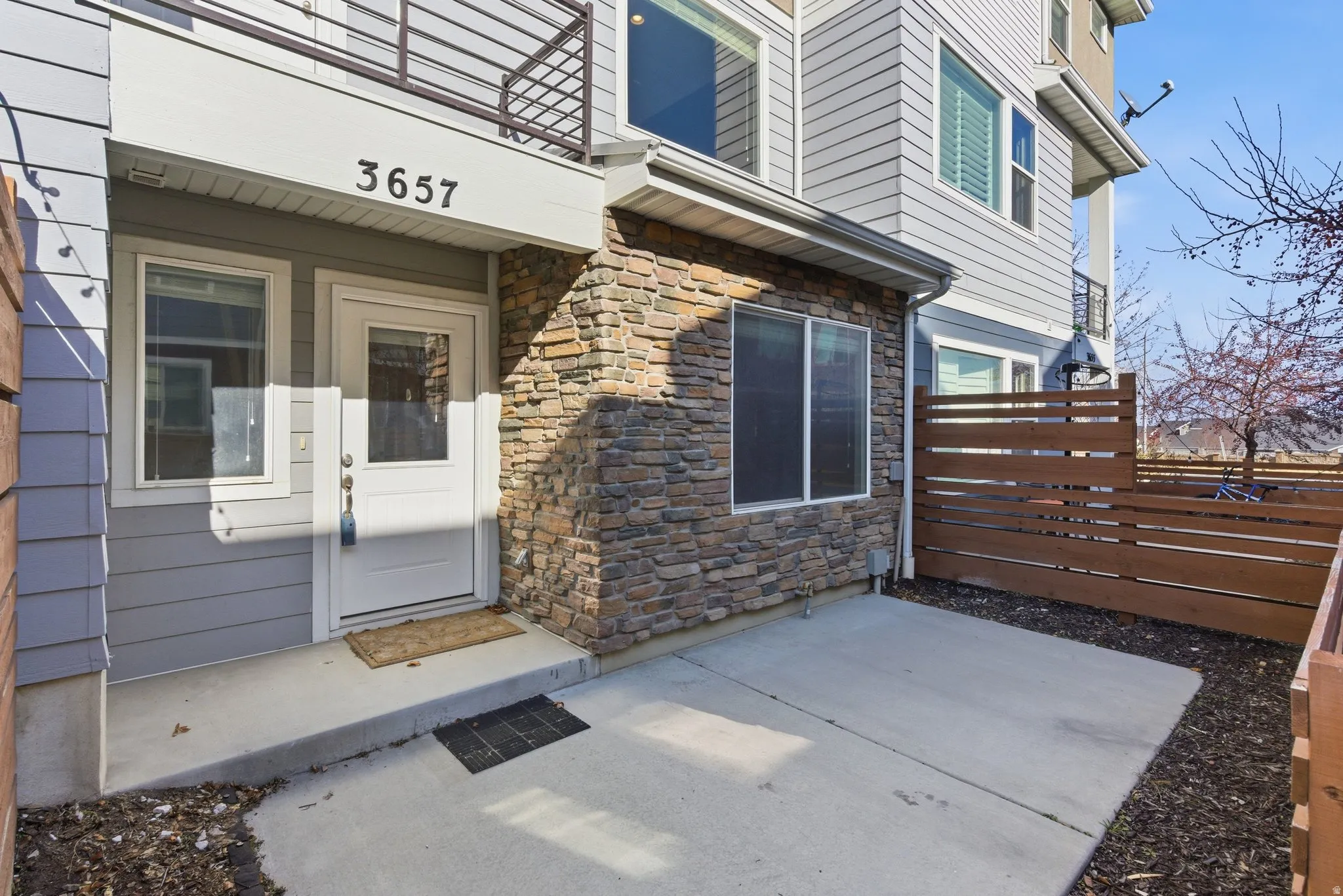 Stone veneer and siding exterior with a private patio space