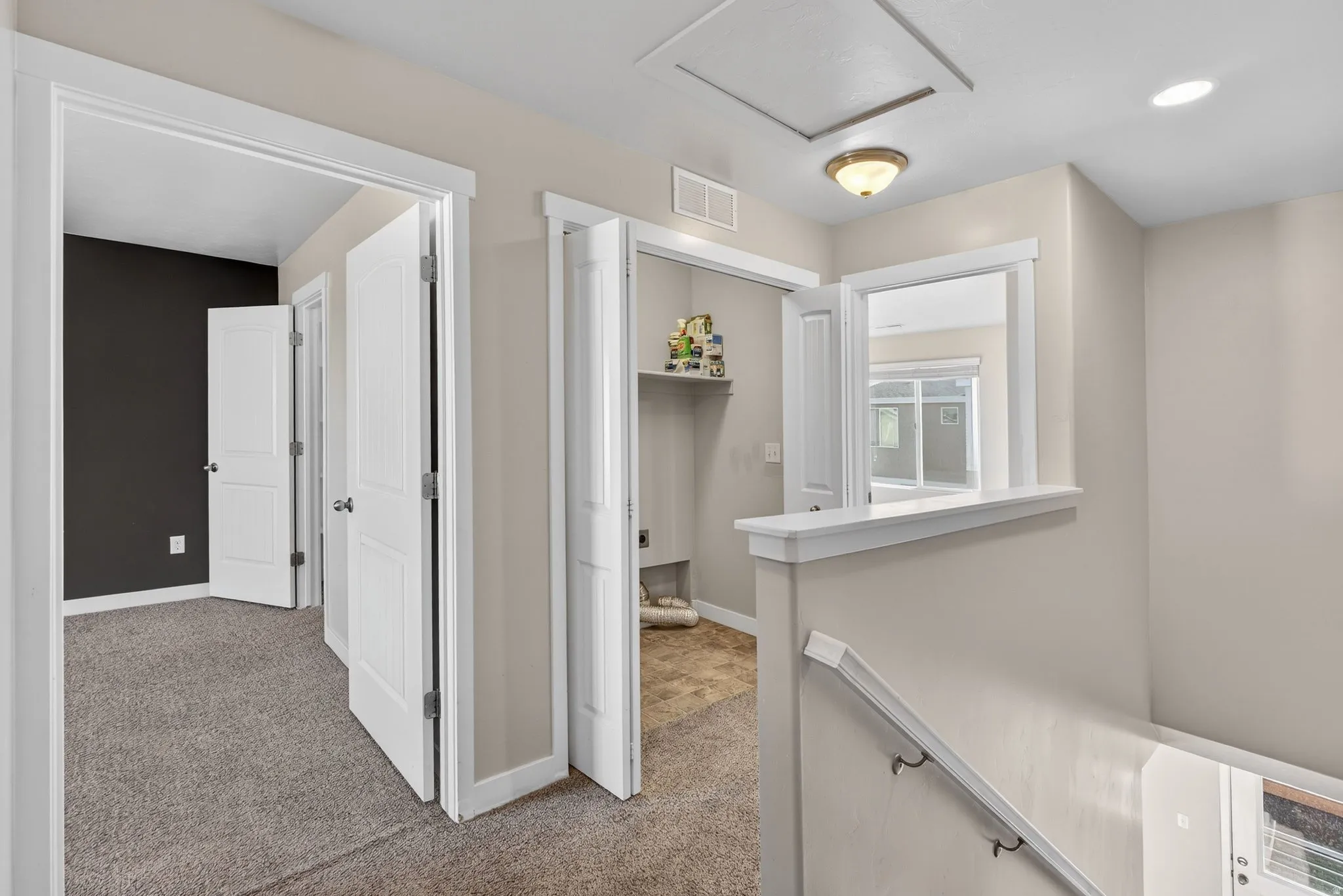 Carpeted hallway with white trim, multiple paneled doors, and a built-in shelf