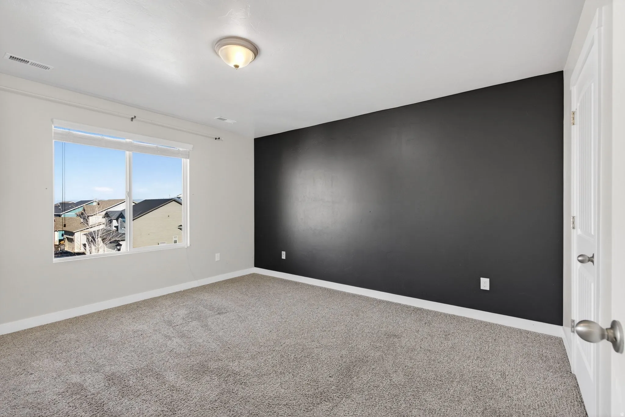 Neutral wall color with an accent wall, window with blinds, carpeted flooring, and a flush-mount ceiling light fixture