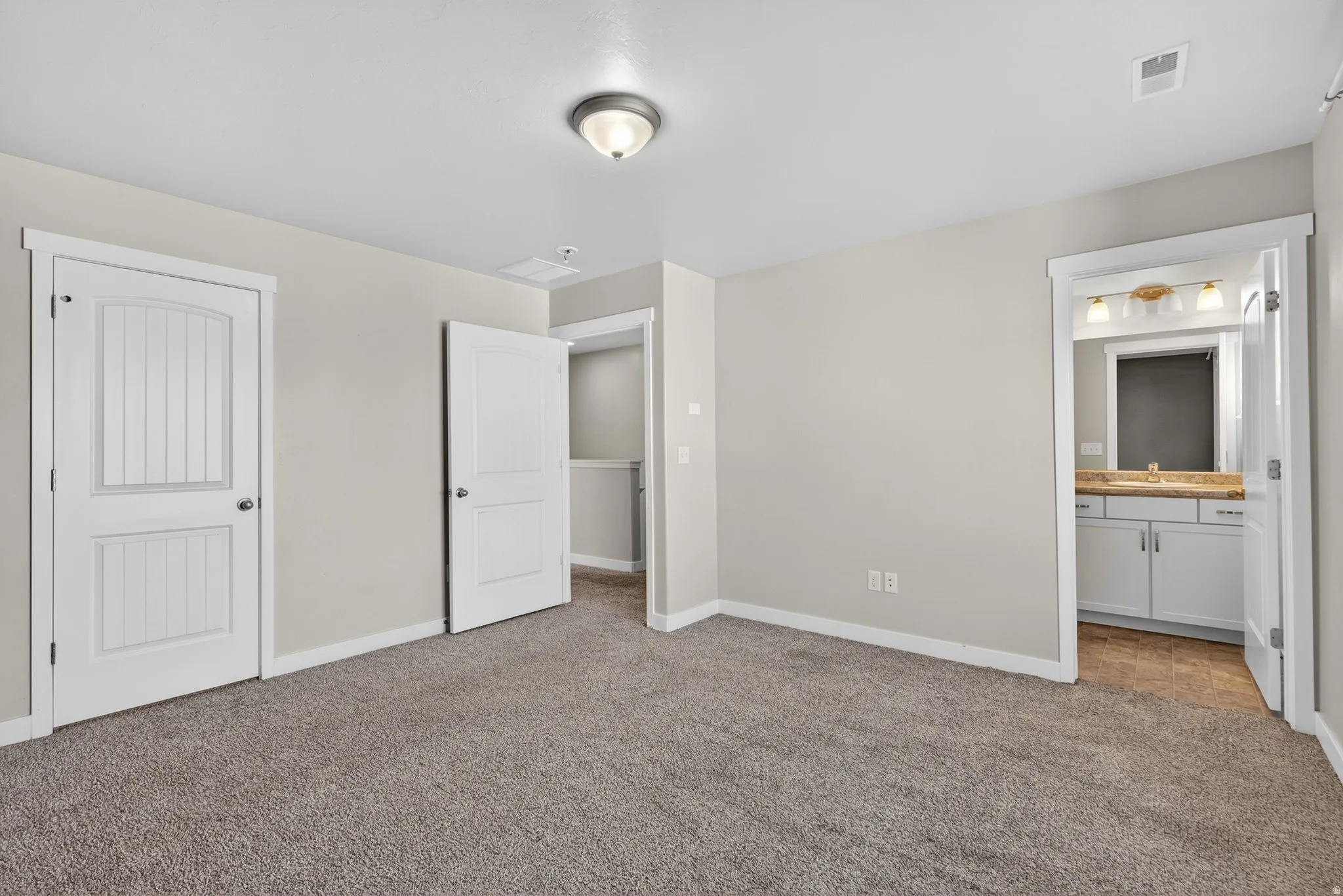 Plush carpet flooring, neutral wall paint, white trim, recessed lighting, and a white vanity with a light-colored countertop