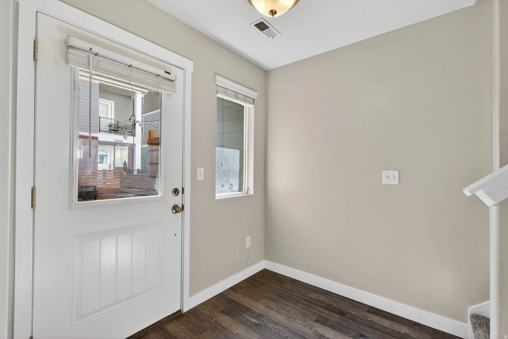 Entryway featuring a white paneled door with glass insert, wood-finish flooring, and neutral wall tones