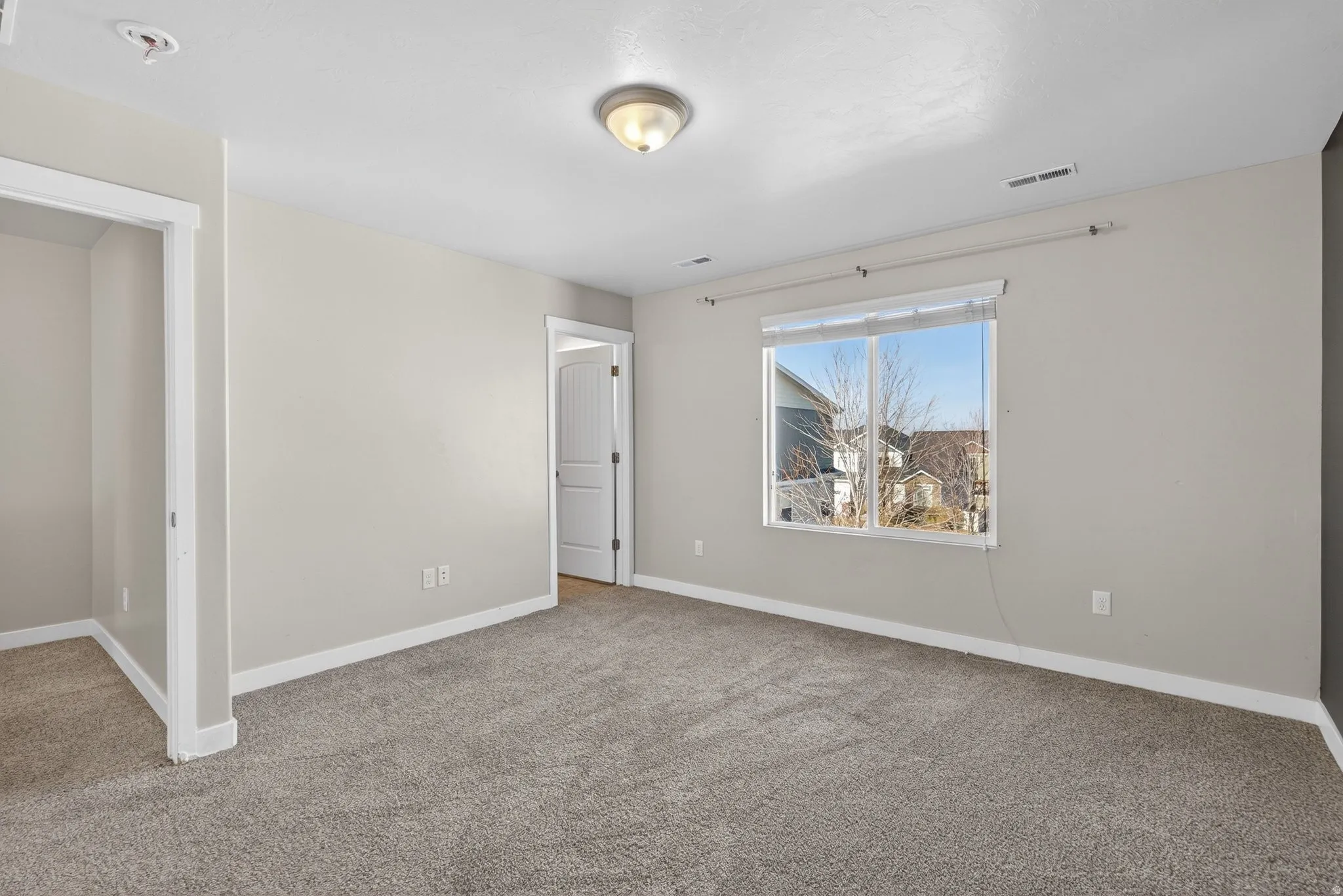 Neutral wall tones, plush carpet flooring, and a ceiling-mounted light fixture