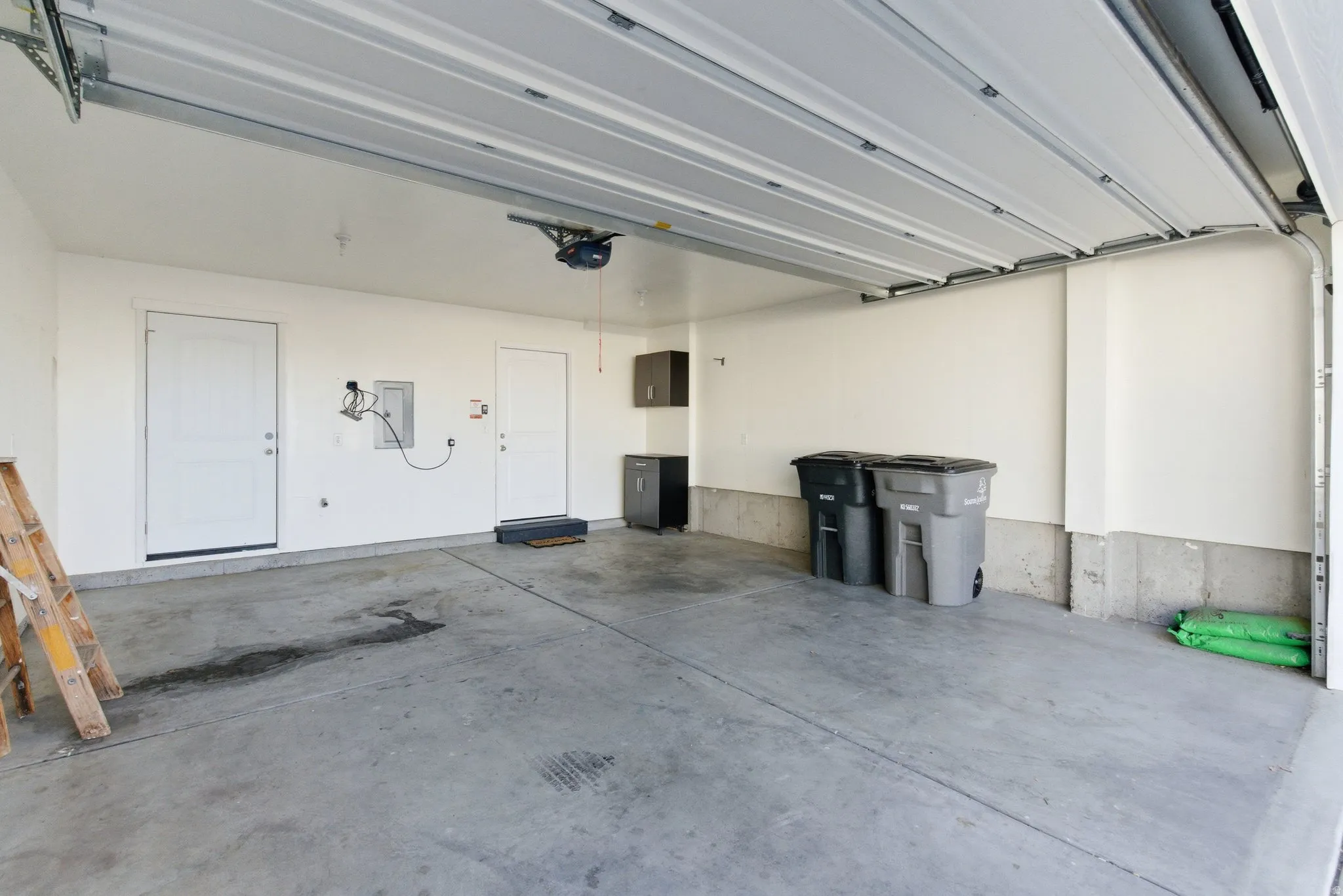 Attached garage with concrete flooring, two access doors, and an overhead garage door