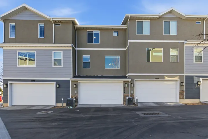 Contemporary townhome exterior featuring a two-car garage, multiple windows, and a blend of stucco and siding finishes