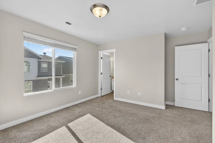 Carpeted room with a large window, neutral wall paint, and white trim