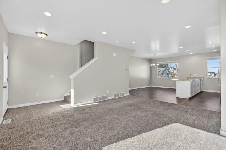Open-concept living space featuring recessed ceiling lighting, neutral wall finishes, and expansive dark wood-finish flooring throughout