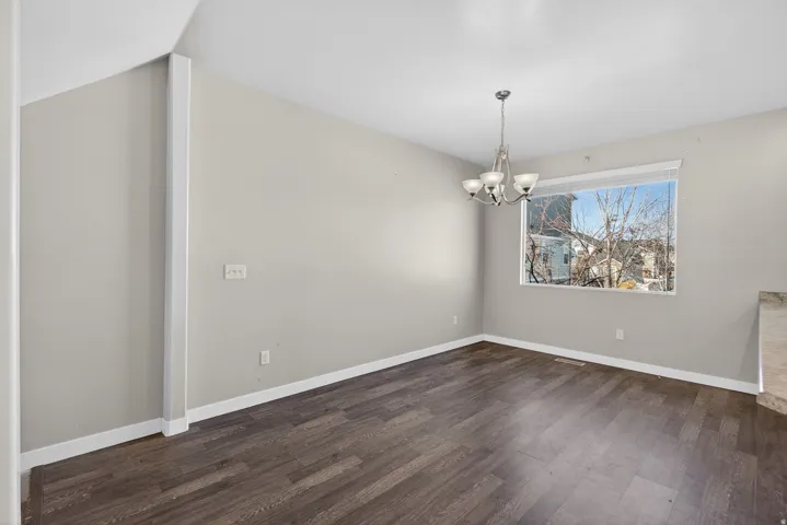 Spacious room featuring wood-finish flooring, a contemporary chandelier, and a large window