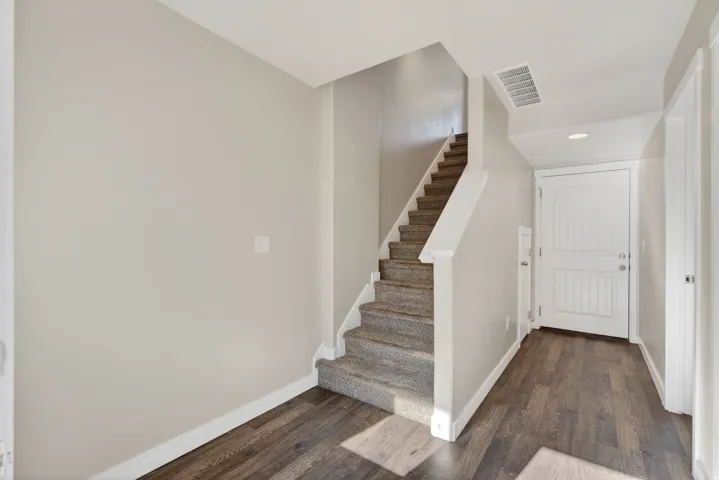 Wood-finish flooring, carpeted staircase, paneled entry door, and recessed lighting
