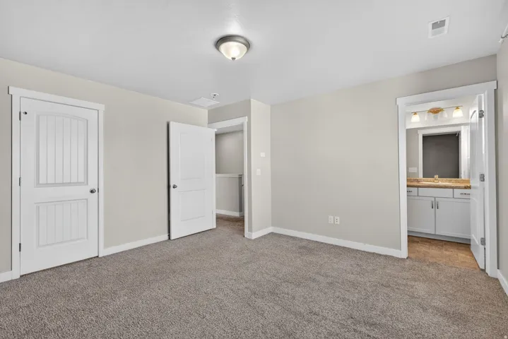 Plush carpet flooring, neutral wall paint, white trim, recessed lighting, and a white vanity with a light-colored countertop