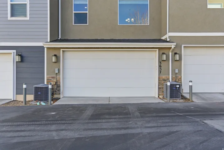Attached two-car garage with overhead lighting and stone accents