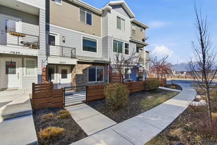 Modern townhome exterior with mixed material siding, stone accents, and a private fenced patio