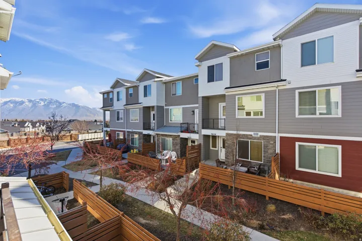 Multi-level townhome exteriors featuring horizontal siding, stone veneer accents, individual patios with wood privacy fencing, and second-story balconies with metal railings