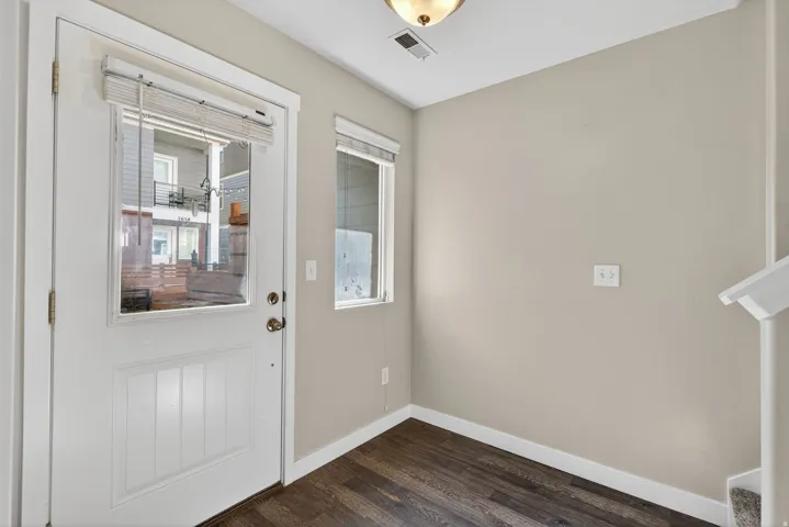 Entryway featuring a white paneled door with glass insert, wood-finish flooring, and neutral wall tones